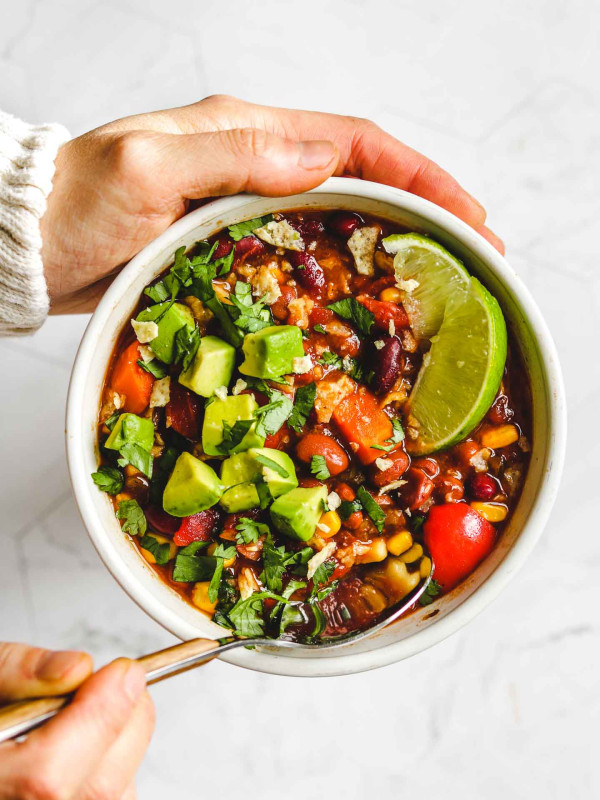 holding a bowl of Instant Pot Vegan Chili in a white bowl