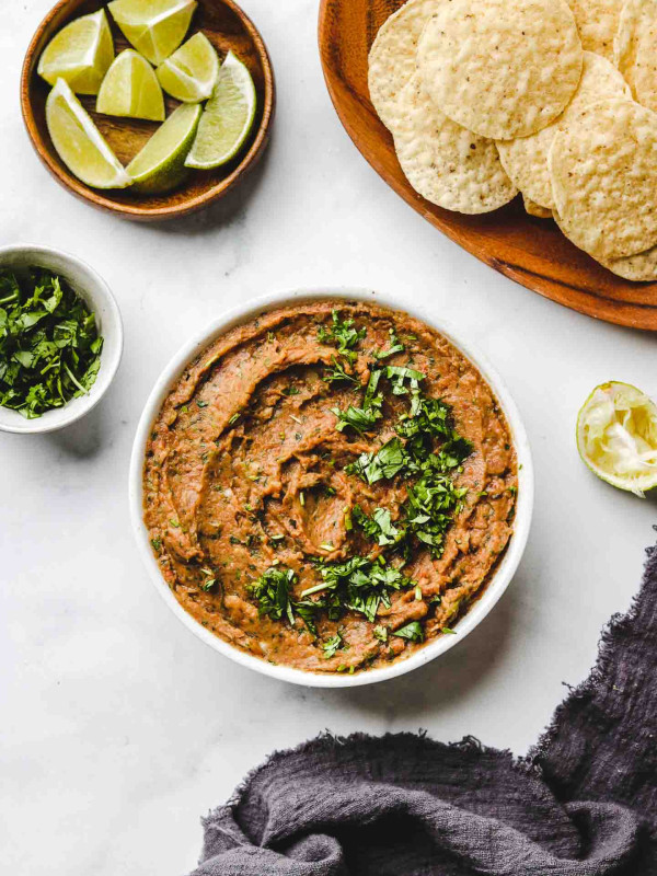 vegan refried bean dip in a white bowl with cilantro