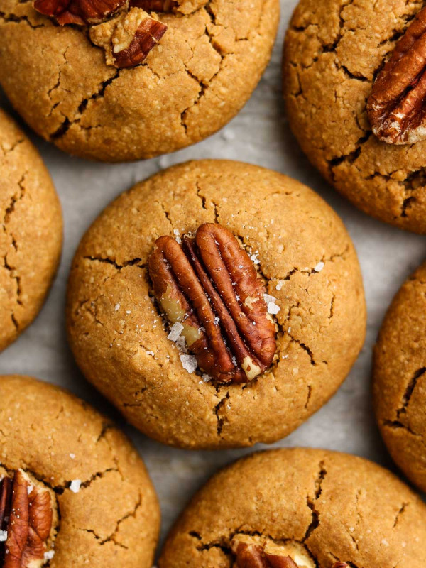 gluten free browned coconut butter maple pecan cookies on parchment paper with flaky salt