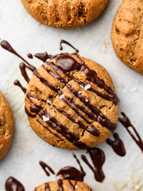 flourless peanut butter cookies with chocolate drizzle and flaky salt on parchment paper