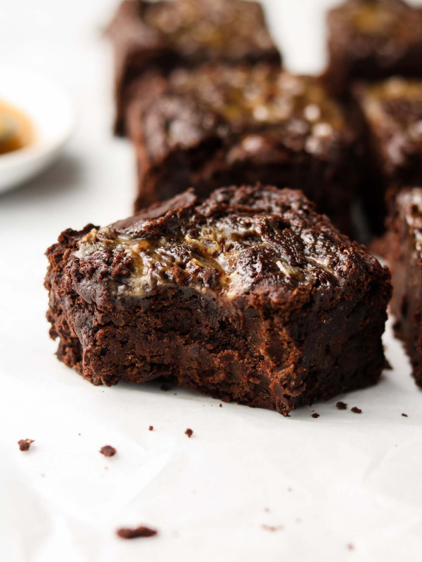 fudgy eggless black bean brownies on parchment paper with caramel sauce bite shot