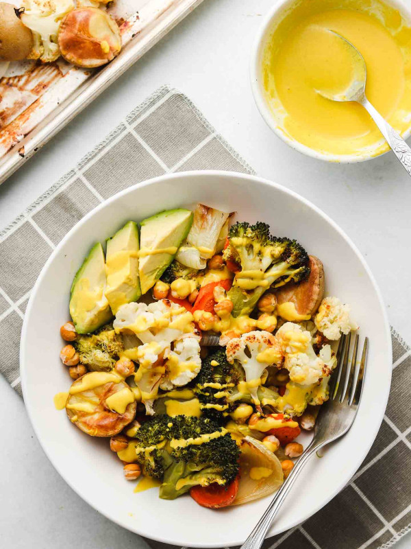 sheet pan roasted vegetables in a bowl with tahini sauce