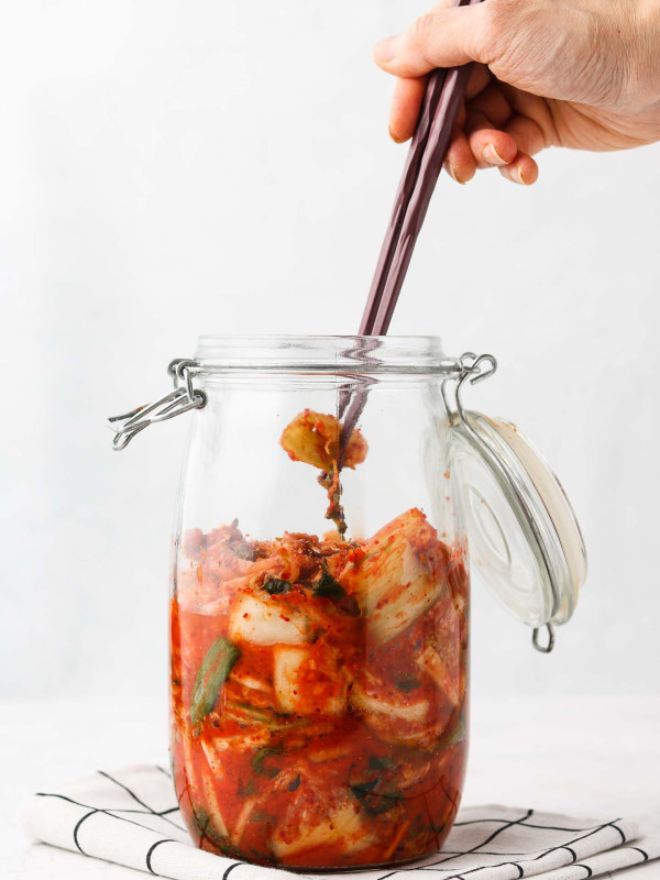 picking up vegan kimchi with chop sticks from a jar