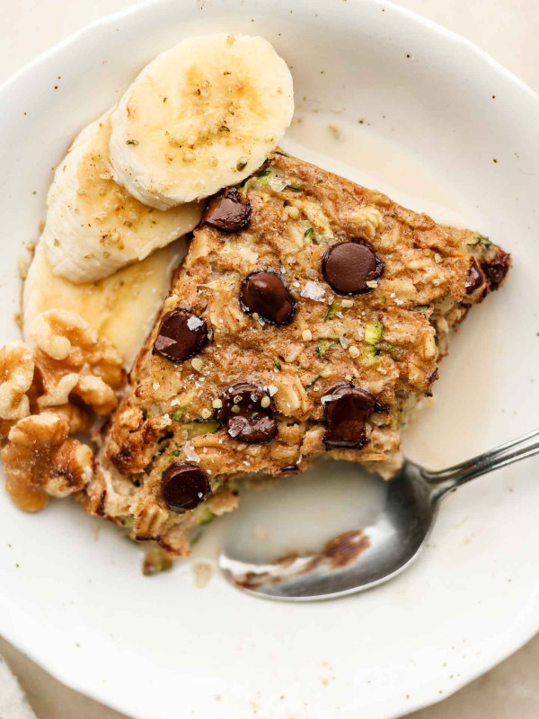 close up shot of baked oats in a bowl with milk and bananas