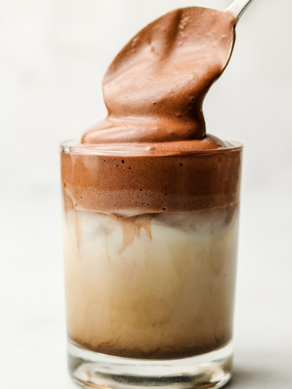 adding whipped chocolate on top of a iced latte