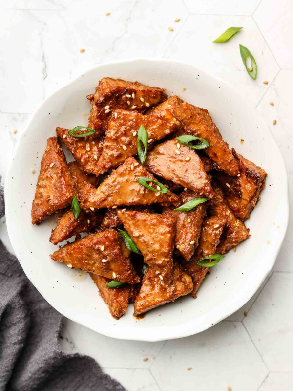 peanut tempeh in a white bowl with scallions on top
