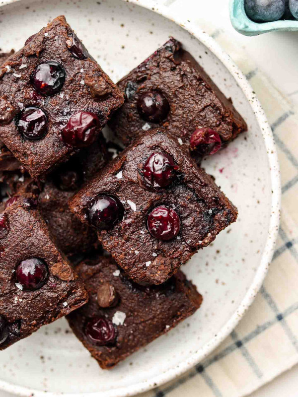 close up shot of blueberry vegan brownies on a speckled white plate