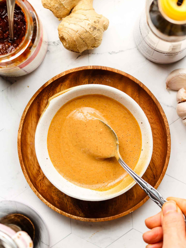 peanut sauce in a white bowl on top of a wooden plate