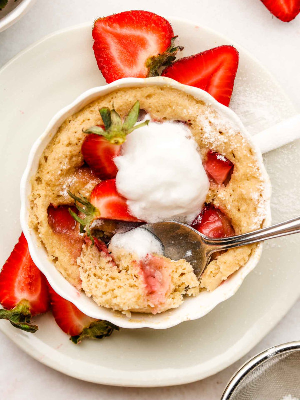 strawberry shortcake in a mug with whip cream on top and a spoon