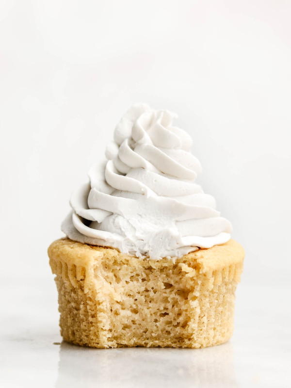 vanilla cupcake with a bite shot and coconut whip cream frosting on top