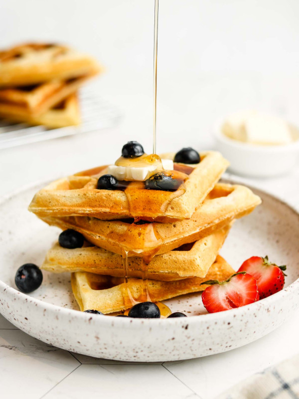 maple syrup pour shot on oat flour waffles with vegan butter and blueberries