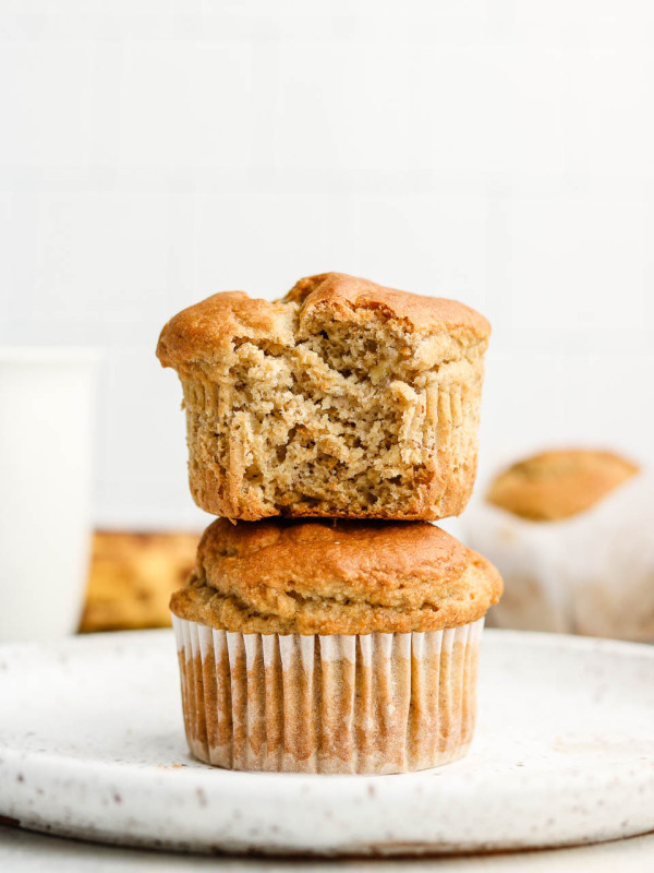super fluffy gluten free banana muffins stacked with a bite taken out of the top muffin