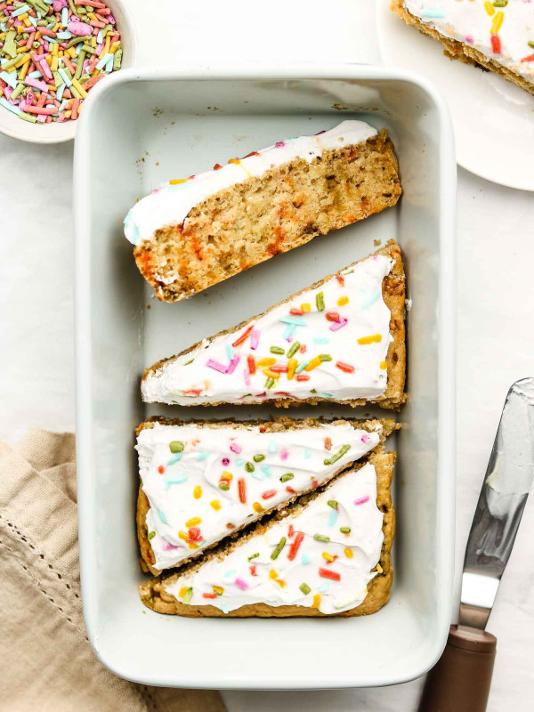 vegan funfetti cake cut into triangle slices in a blue loaf pan