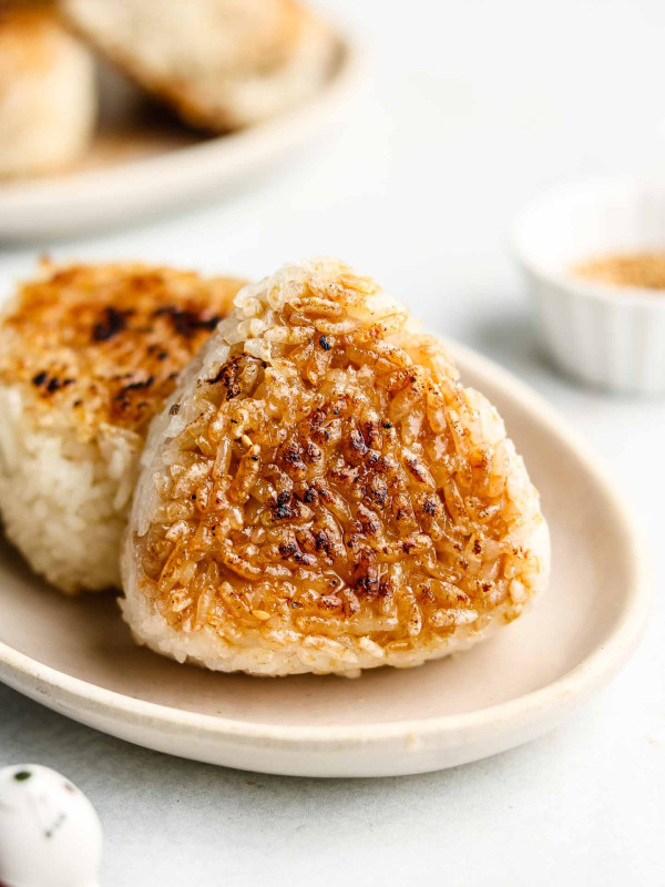 grilled japanese rice ball on a ceramic white plate with soy sauce on it