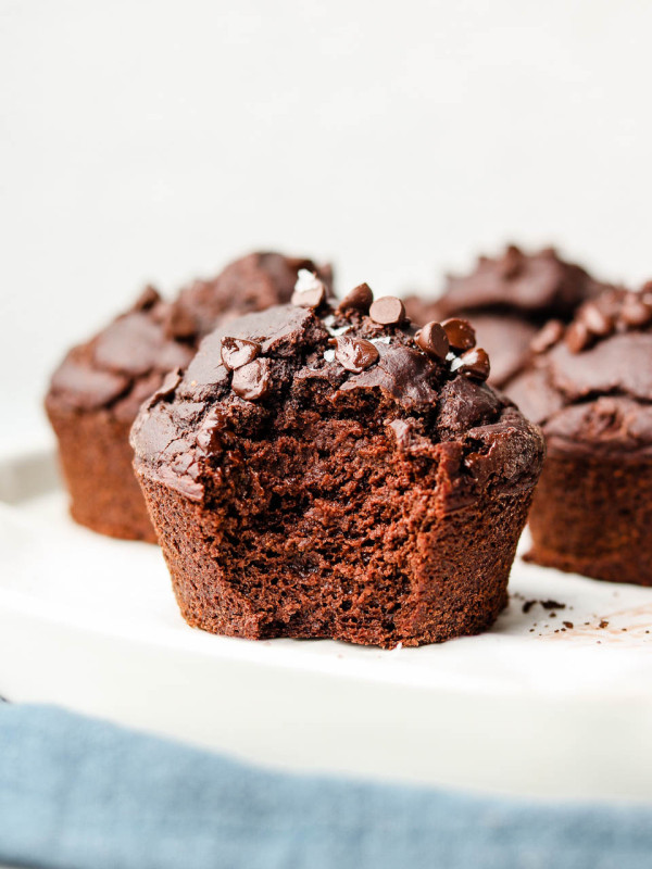 vegan chocolate muffin with a bite in it on a white plate