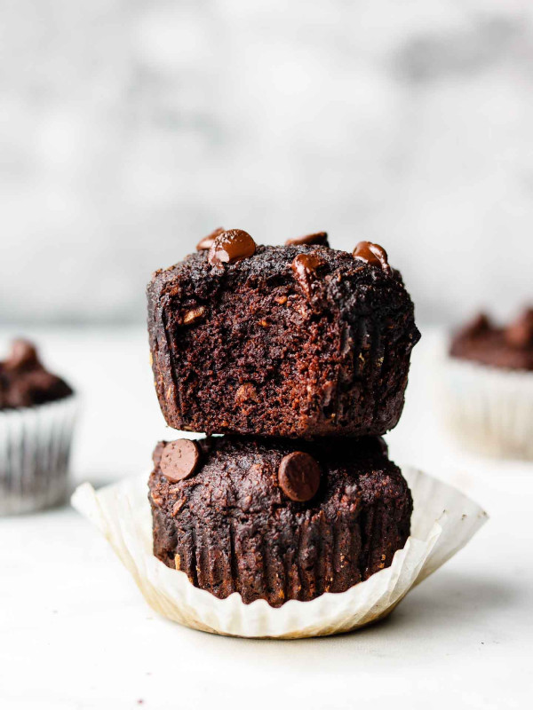 stack of triple chocolate muffins with a bite in the top muffin