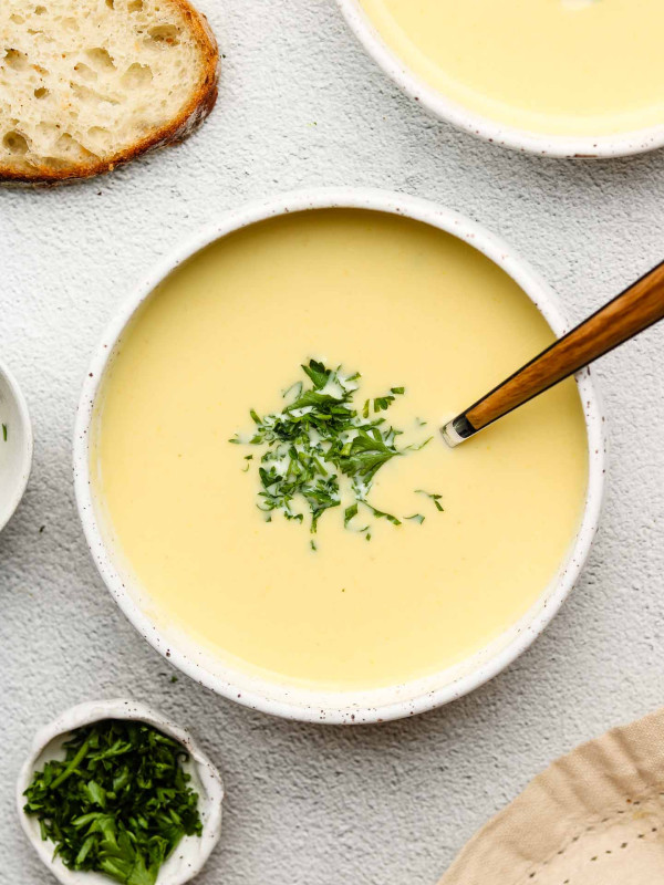 japanese corn potage in a white bowl topped with parsley and a spoon inside