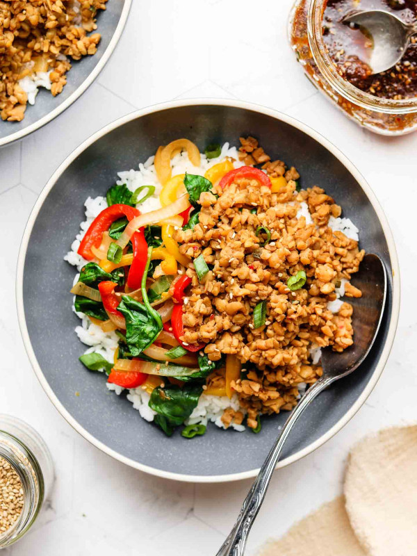 korean bbq tempeh beef over white rice and veggies in a blue bowl