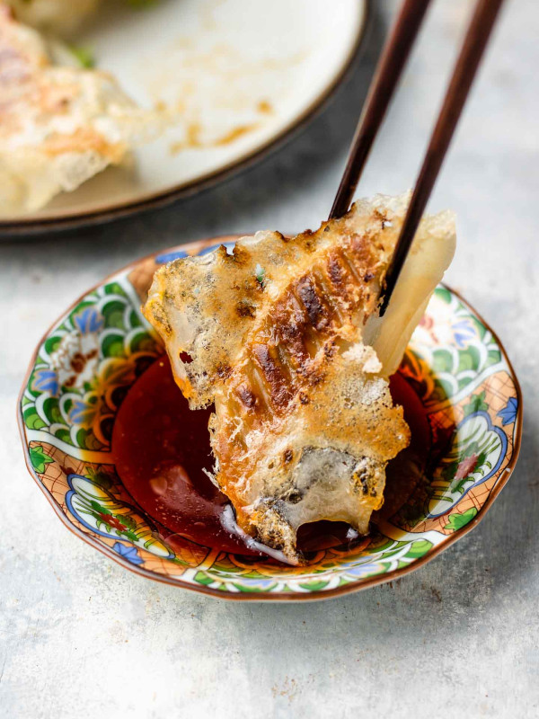 crispy gyoza dipping in rice vinegar, soy sauce and chili oil sauce in a small japanese plate