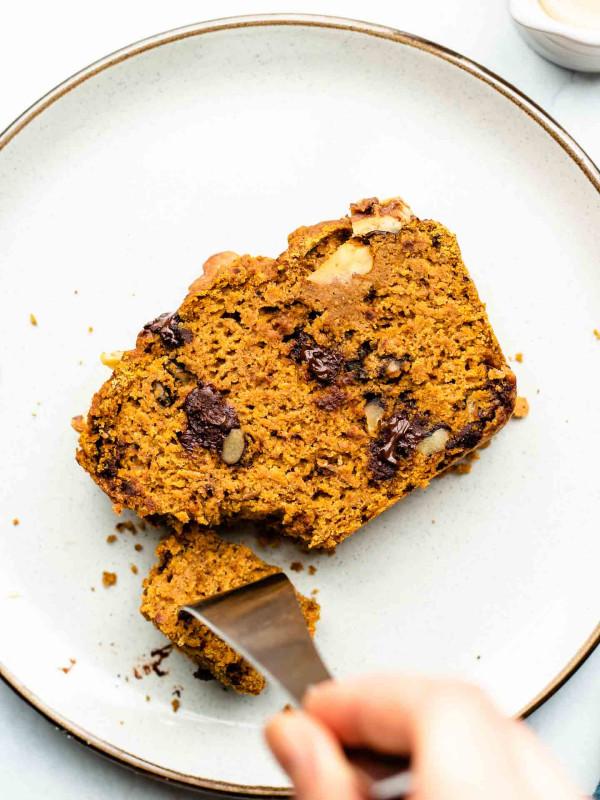 fork slicing into a piece of pumpkin bread on a white plate