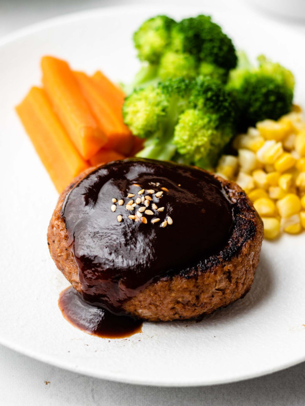 close up shot of hamburger steak with red wine reduction sauce over it