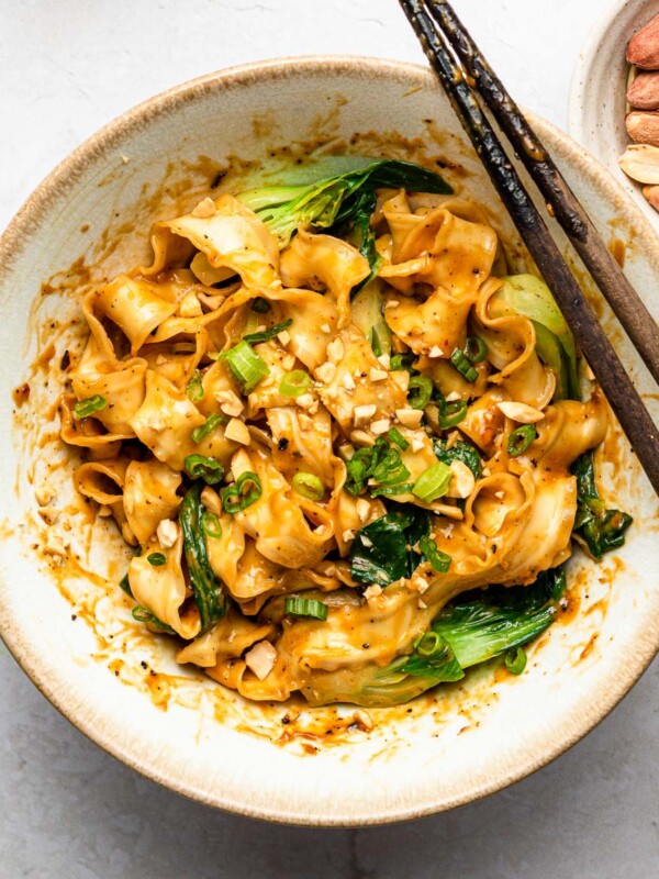 spicy peanut noodles with bok choy in a white bowl