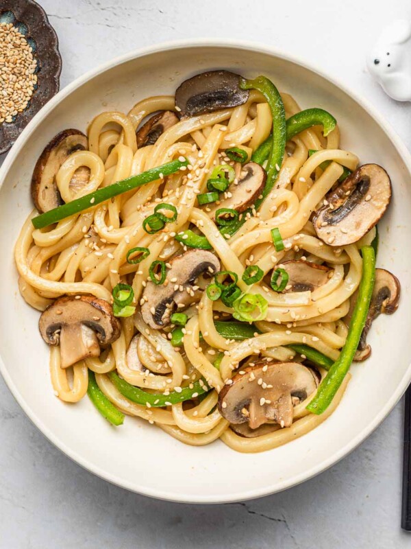 shoyu butter udon noodles with mushrooms and vegetables in a white bowl with sesame seeds