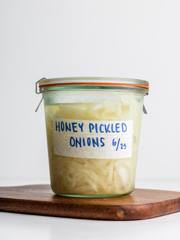 weck jar with pickled onions on a wooden cutting board