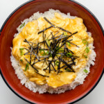 tamagoyaki soft scramble over rice in a bowl with seaweed and scallions