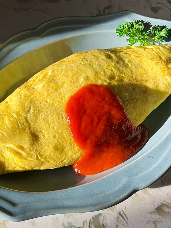 omurice on a blue plate with ketchup sauce