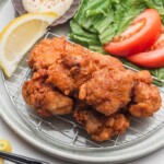 chicken karaage on a wire rack with lemon and side salad
