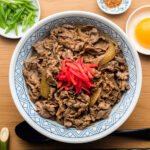 yoshinoya beef bowl in a donburi with pickled ginger on top
