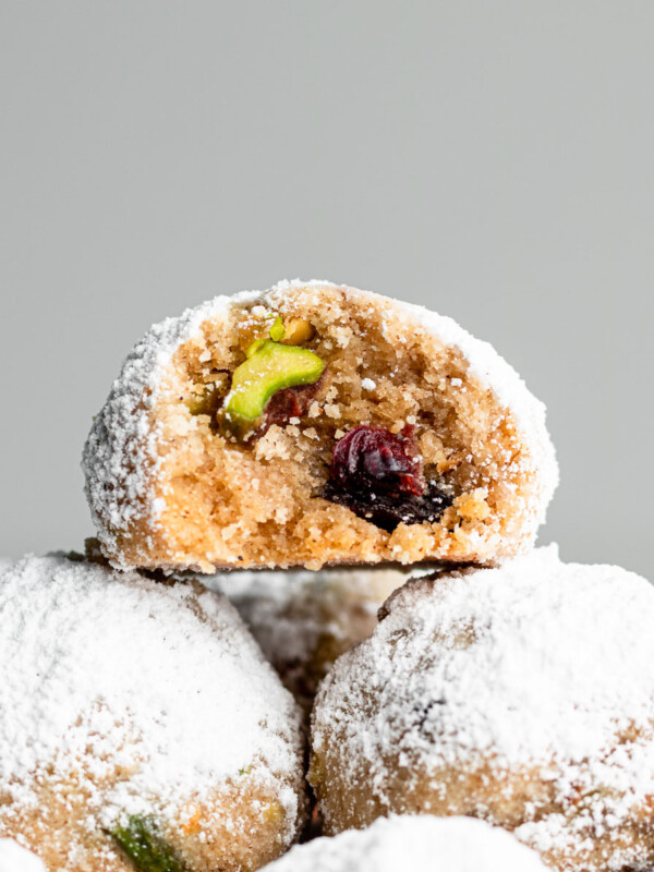 stollen snowball cookies with pistachios and dried cranberries with a bite taken out of the cookie
