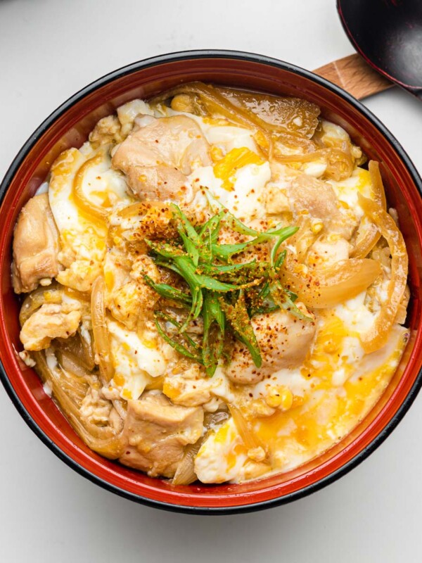rice cooker oyakodon in a red bowl with green onions on top