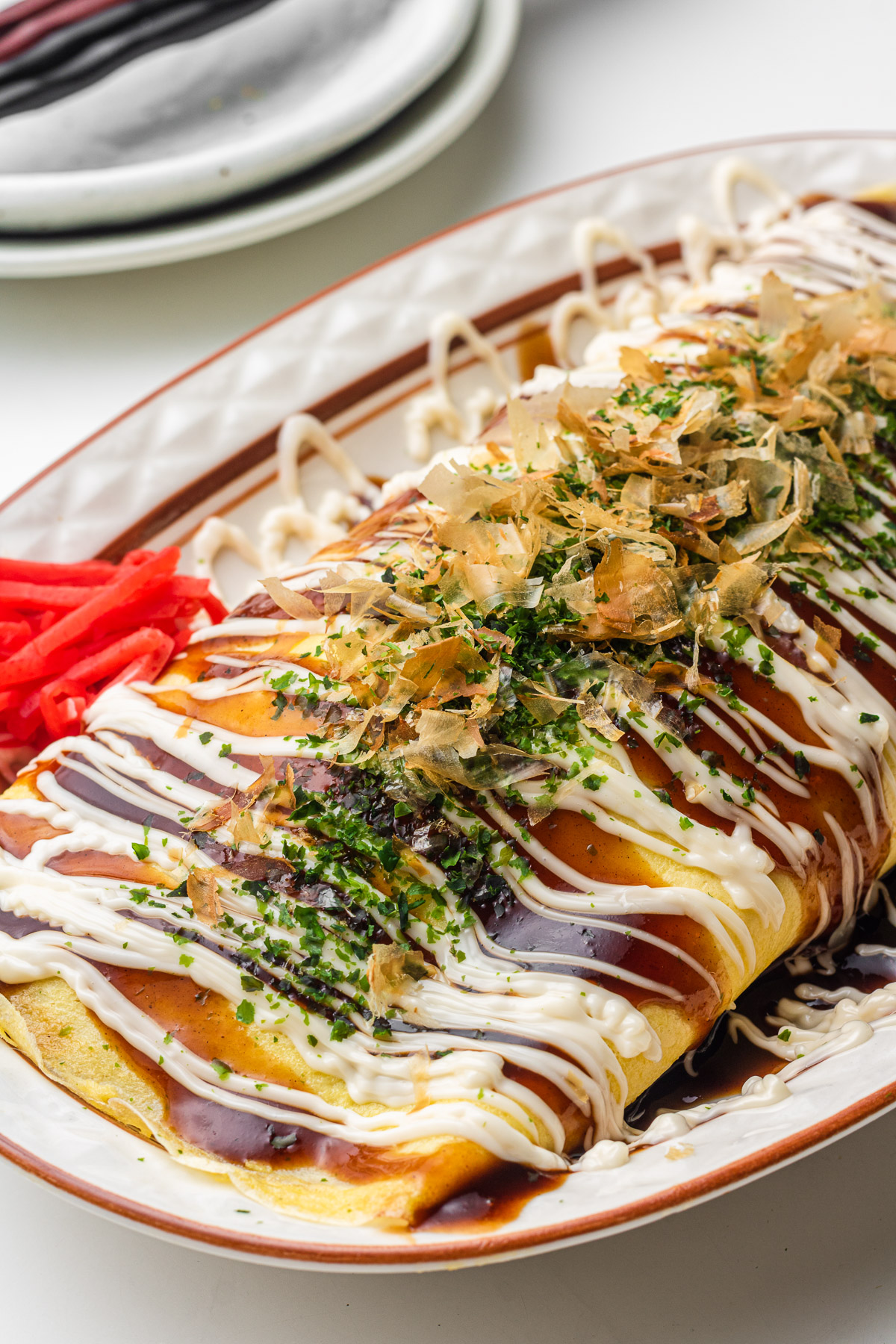 japanese pork cabbage omelette with okonomiyaki sauce on a oval plate