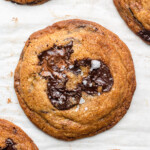 brown butter chocolate chip cookies on parchment paper with fancy salt on top