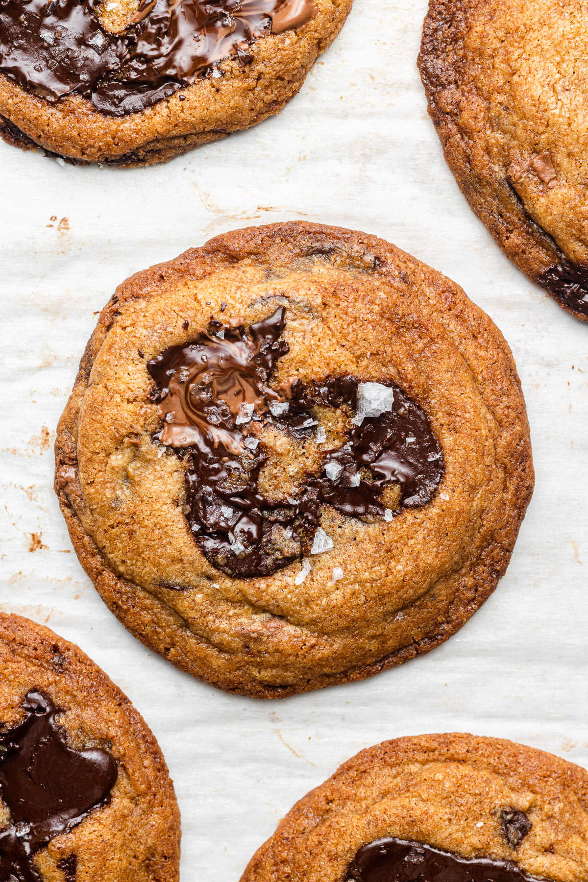brown butter chocolate chip cookies on parchment paper with fancy salt on top