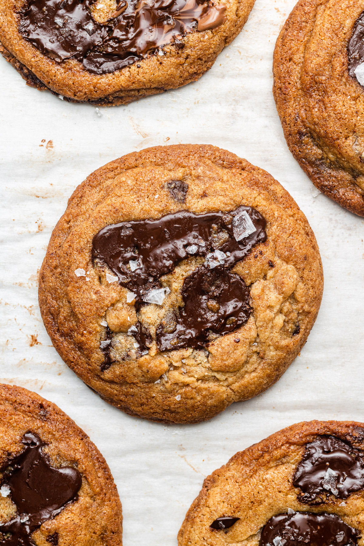 brown butter chocolate chunk cookies on parchment paper with fancy salt on top
