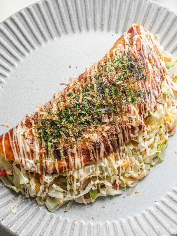 japanese cabbage pancake with mayo and okonomiyaki sauce on a blue plate