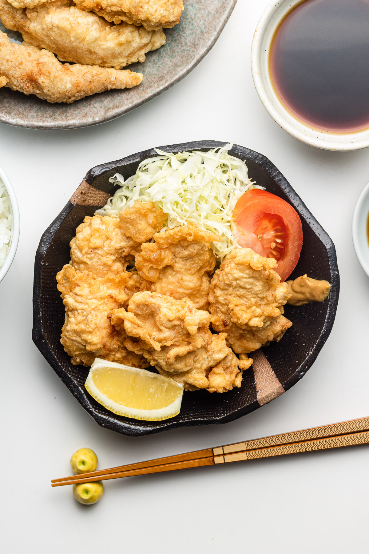chicken tempura with cabbage, tomatoes and lemon on a black plate