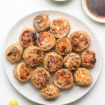 crispy rice paper rolled dumplings on a white plate with creamy mayo sauce and dumpling sauce on the side