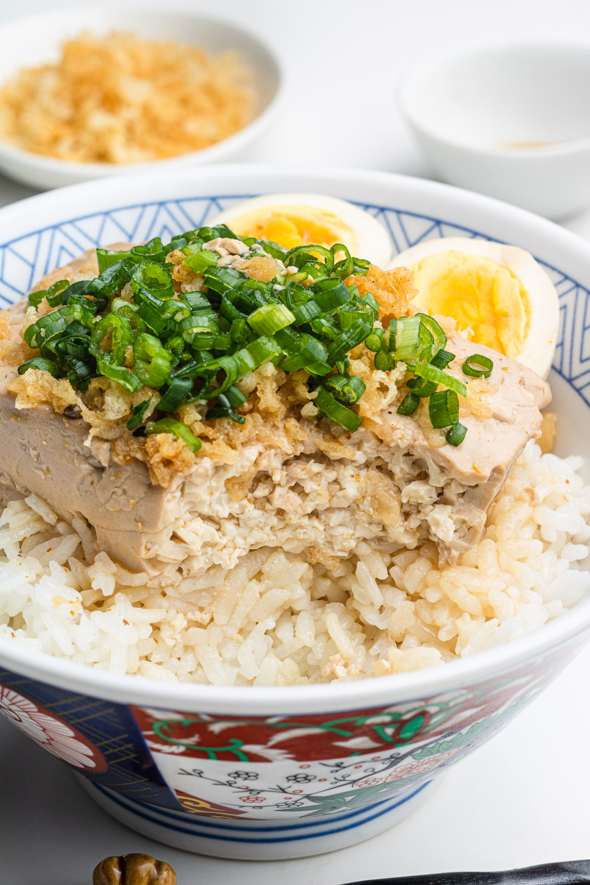 tofu and eggs (toumeshi) over rice in a donburi bowl with scallions and tempura scraps on top