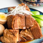 kakuni on a blue plate with scallion, eggs and bok choy