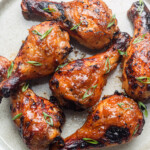 sticky asian chicken drumsticks on a ceramic plate