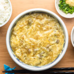 egg drop soup over udon and leftover japanese curry in a blue bowl served with ginger, scallions and rice