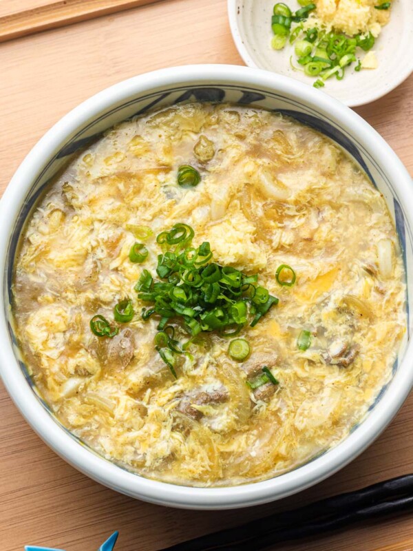 egg drop soup over udon and leftover Japanese curry topped with green onions in a blue bowl