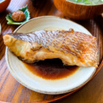 simmered sea bream on a white plate with braising liquid