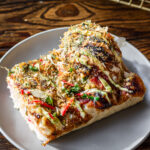 slice of okonomiyaki focaccia on a white plate