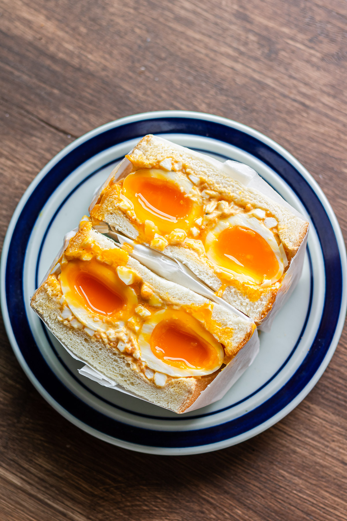 soft boiled tamago sando with japanese milk bread on a blue plate