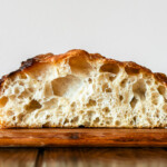 big bubbly open crumb focaccia sliced on a wooden cutting board